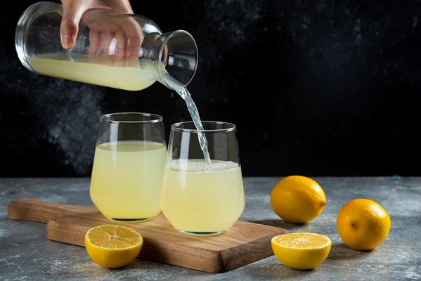 a hand pouring lemon juice in a glass cup - Салат с киви и пекинской капустой