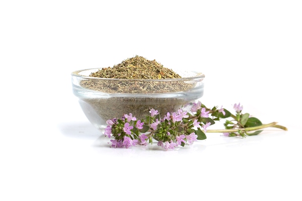 a mound of dried thyme grass in a glass bowl and a flowering branch of a medicinal thyme plant on a white background - Булгур с овощами
