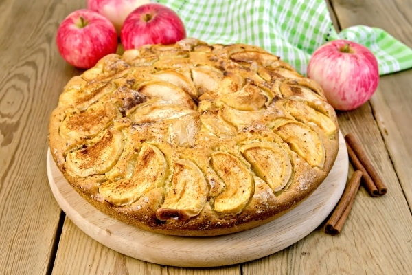 a sweet whole apple pie napkin cinnamon on a wooden boards background - Шарлотка на скорую руку