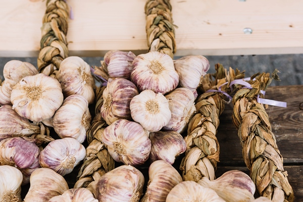 an overhead view of garlic bulb braids on wooden table - Как лучше сохранить продукты?