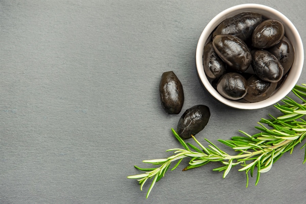 black olives bella di cerignola italian olives colored olives and a sprig of rosemary lie on a black stone countertop culinary banner or poster for advertising with place for - Как лучше сохранить продукты?