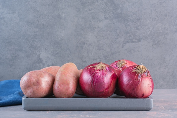 black plate of sweet potatoes and red onions on stone surface - Шанежки на кефире с картошкой