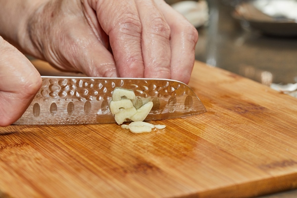chef cuts garlic on a wooden board in the kitchen - Русский хлебный суп