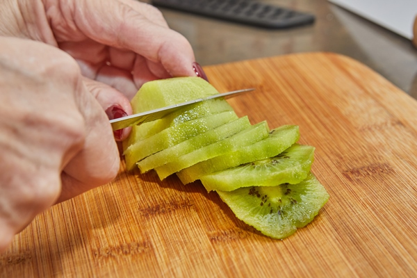 chef is preparing kiwi pie cut the kiwi into slices - Салат с киви и пекинской капустой