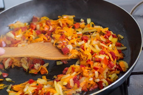 cooking a roast for soup of onions carrots paprika tomatoes herbs and spices in sunflower oil in a frying pan - Постные котлеты из фасоли