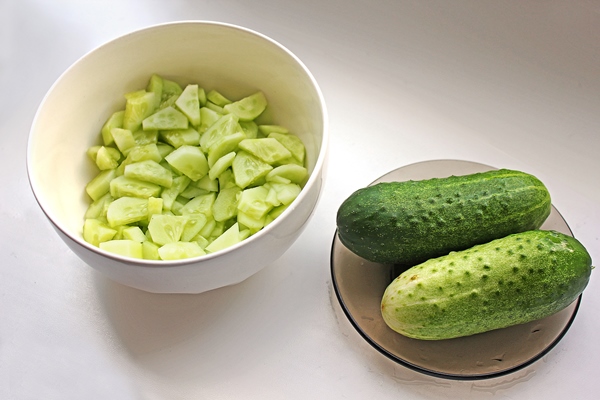 cucumbers in a small plate and sliced cucumbers in a white bowl on white background - Окрошка с солёными грибами