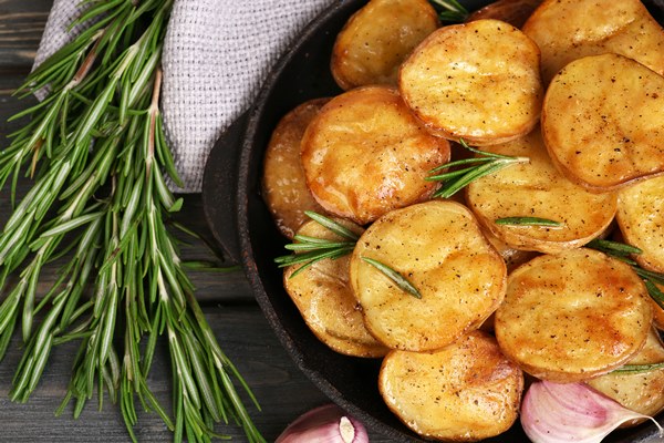 delicious baked potato with rosemary frying pan table close up - Картофель, запечённый в духовке