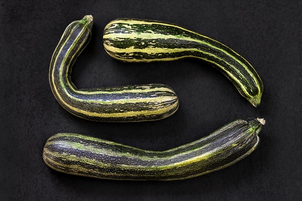 fresh zucchini on black textured surface - Кабачковая икра с сельдереем