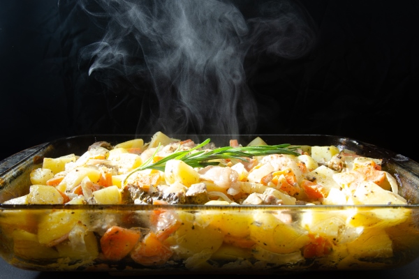 hot potatoes in the oven with meat and vegetables on a black background - Запеканки в духовке: правила приготовления