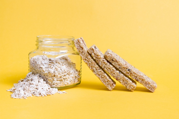 jar of oatmeal and cereal bars on yellow background - Постный овсяный десерт с орешками и сухофруктами