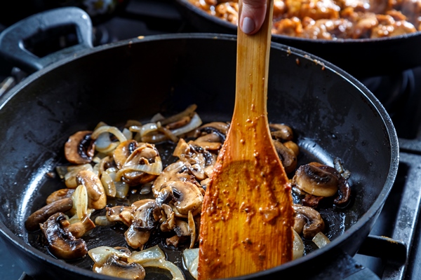 mushrooms fried with onions in a deep frying pan with a wooden spatula - Гречневые тефтели с грибами и зеленью