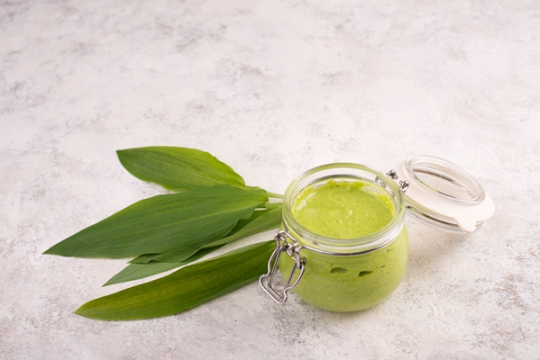 pesto made from wild garlic pine nuts and feta cheese in a glass with fresh leaves on a white - Постный майонез
