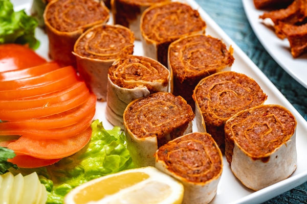 side view lahmacun roll with lettuce sliced tomatoes and slice of lemon on a plate - Постный бездрожжевой лаваш