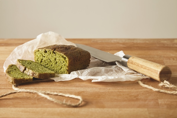 sliced green rustic healthy bread from spinach dough isolated with antic knife cutting wooden board white background - Австралийский овощной хлеб