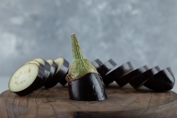 sliced raw eggplant on wooden board close up photo - Маринованные баклажаны с кардамоном