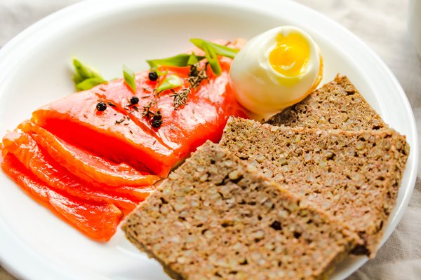 slices of salted raw fish fillet with egg and piece of buckwheat gluten free bread paleo diet meal healthy high protein and low carbohydrate products concept - Гречневые постные хлебцы