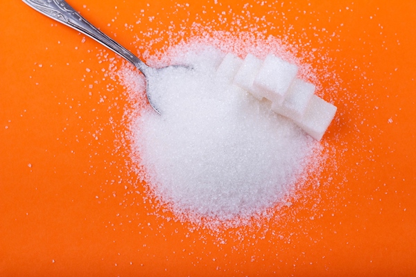 spoon and cubes of white sugar and granulated sugar on an orange background - Дыня в сиропе