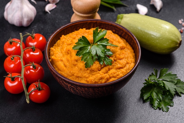 squash caviar with garlic and tomatoes in a rustic bowl on a dark background - Кабачковая икра с сельдереем