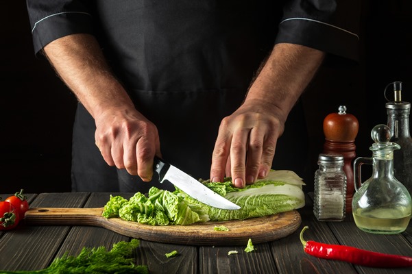 the chef cuts peking cabbage with a knife - Салат с киви и пекинской капустой