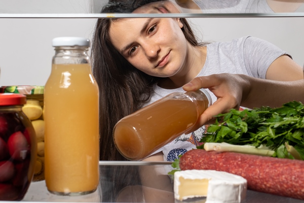 the girl looks in the fridge and takes out fruit juice in a glass bottle - Советы по выбору рецептов