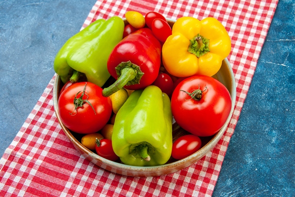 top view fresh vegetables cherry tomatoes different colors bell peppers tomatoes cumcuat on platter on red and white checkered tablecloth on blue table - Как лучше сохранить продукты?