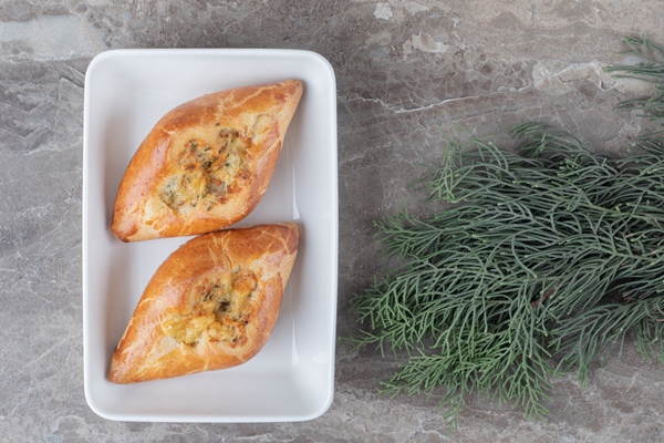 two small turkish pides platter pine branches marble surface - Рыбные расстегаи