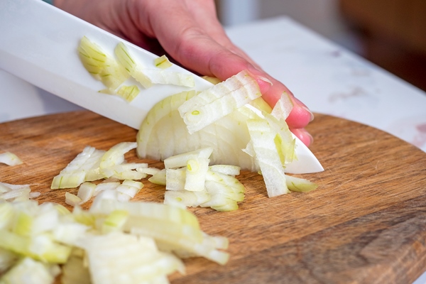 white onions are cut with a knife on a wooden board the concept of cooking - Салат слоёный с ананасом