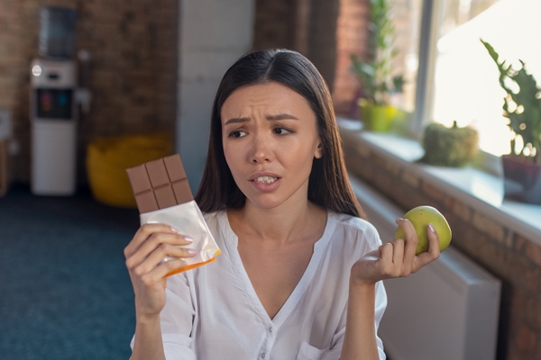 woman wanting to choose chocolate while understanding that it is not healthy - Полезные домашние сладости
