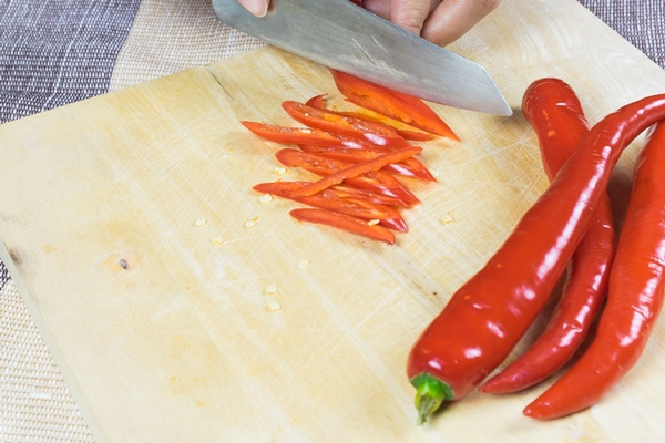 women sliced peppers on wood plate - Острая маринованная свёкла