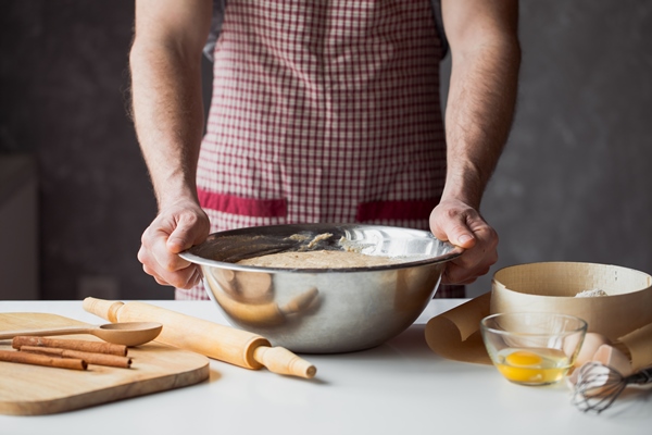 a handful of flour with egg on a rustic kitchen against the table of men s hands knead the dough - Кулич пасхальный