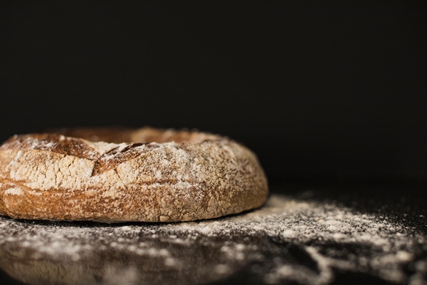 baked bread bun dusted on flour against black background - Библия о пище