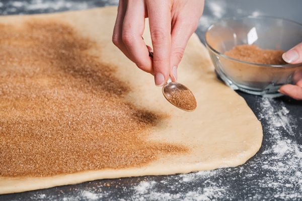 baker sprinkles on the dough sugar with cinnamon for tasty buns - Пасхальный венок