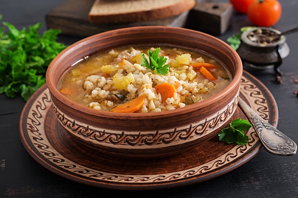 barley soup with carrots tomato celery and meat on a dark surface - Рассольник с перловкой на зиму