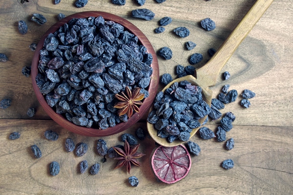 black raisins in a bowl on a wooden table black raisins dry citruses and anise stars top view - Пасхальный кулич