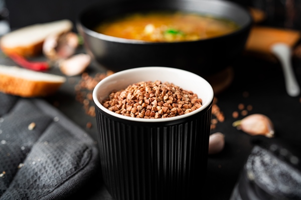 buckwheat for soup on a dark background in black bowl high quality photo - Диетический куриный суп с гречкой и грибами