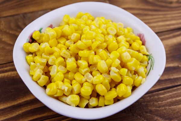 canned sweet corn in a bowl on wooden table - Салат «Шпротный»