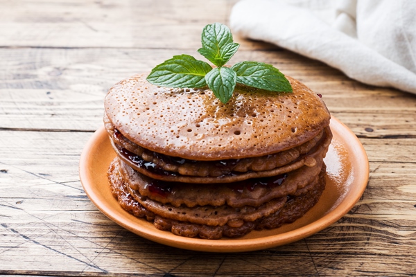 chocolate pancakes with berry jam and mint for breakfast on wooden table - Постные блинчики с какао