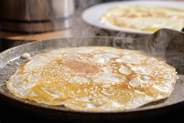 close up of frying pancake in a pan - Постные рисово-кокосовые блинчики