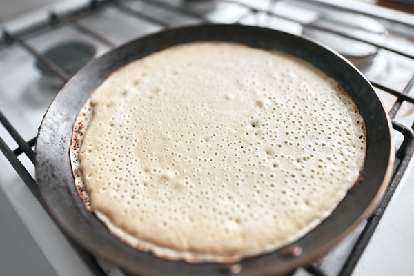 close up raw side of the pancake on cast iron pan homemade tasty breakfast - Блинцы быстрые на воде