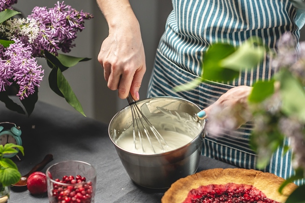 cooking homemade cranberry pie a female pastry chef is whipping up a whisk of sour cream - Песочный пирог без яиц