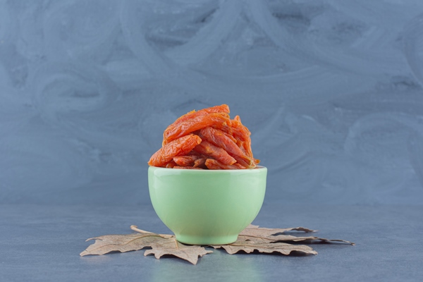 delectable dried apricot in the bowl on the leaf on the marble background - Пасха с курагой 