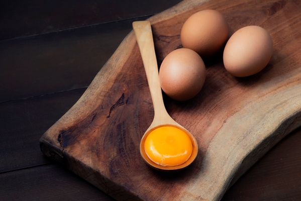 food ingredients egg yolks for serving on a spoon wooden floor and raw eggs on wood background - Кулич домашний