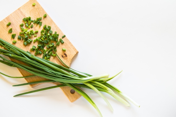 fresh green onion feathers and cut into pieces on a wooden chopping board top view flat lay copying space isolated - Салат из крапивы с зелёным луком