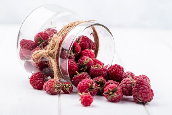 front view of raspberries in a jar on a white surface - Малина в собственном соку