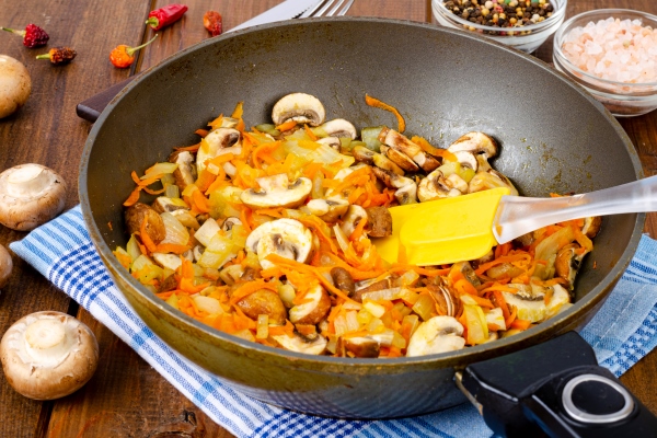 frying pan with fried mushrooms champignons onions and carrots on wooden table - Постный грибной суп с вермишелью