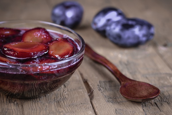 glass bowl with plum jam and berries ripe plums on vintage table - Цукаты из сливы