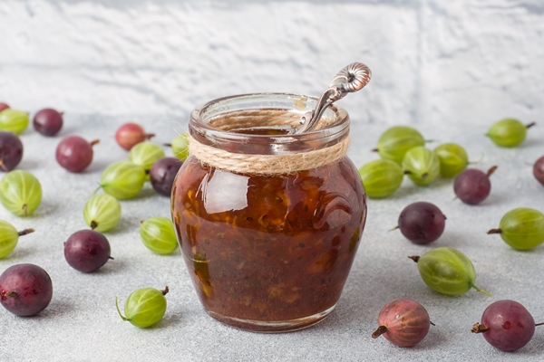 gooseberry jam in a jar with fresh gooseberry berries on a gray surface 1 - Крыжовник с сахаром