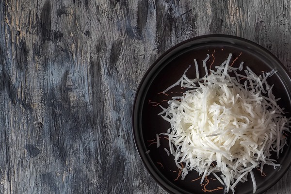 grated daikon in two black ceramic plates and chopsticks top view - Редька с маслом