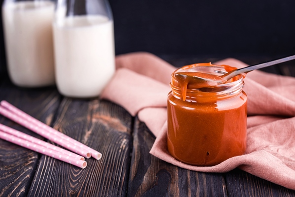 homemade salted caramel on a dark table with a beautiful black spoon and milk - Пасха с кедровыми орешками и кокосом