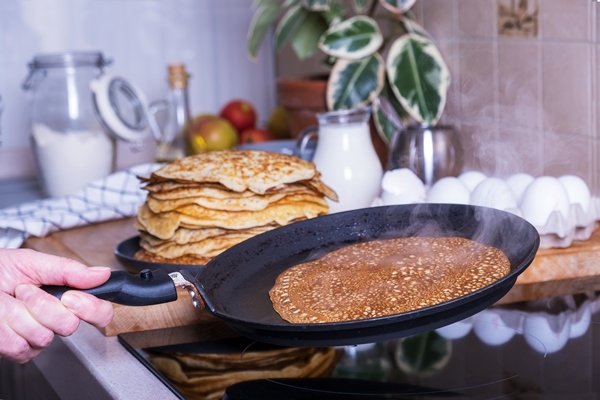 housewife woman bakes pancakes for breakfast home cooking pancakes in pan on glassceramic stove in her kitchen diy ingredients for making pancakes selective focus 2 - Постные блины со свёклой и орешками